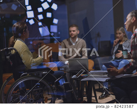 Businesswoman in wheelchair having business meeting with team at modern office Businesswoman in wheelchair having business meeting with team at modern office 82423587