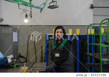 a portrait of a woman in uniform carrying a piece of metal and preparing it for the final part of production 82425396