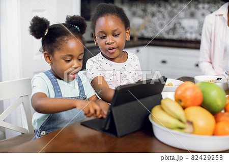 African american sisters using tablet during breakfast 82429253
