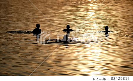 Silhouettes of bathing people on the city lake. 82429812