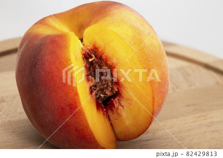 Peaches on a wooden board. Peach in half with a stone. Ripe juicy fruits 82429813