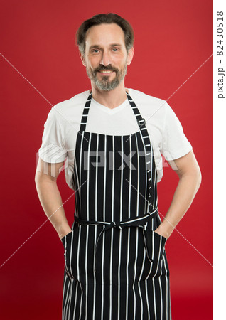 Skilled and confident. Senior cook wearing bib apron.  82430518