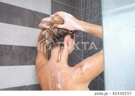Young woman washing her hair with shampoo in shower Young woman washing her hair with shampoo in shower 82430557