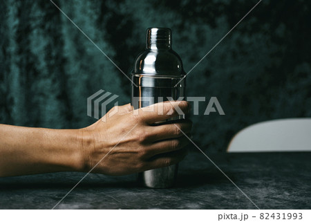 man grabs a metal cocktail shaker from a table 82431993