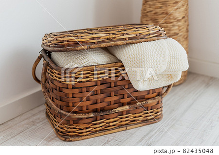 A wicker straw and bamboo chest of drawers, in the interior with bedspreads, blankets, a blanket and towels. For interior decoration. A wicker straw and bamboo chest of drawers, in the interior with bedspreads, blankets, a blanket and towels. For interior decoration. 82435048