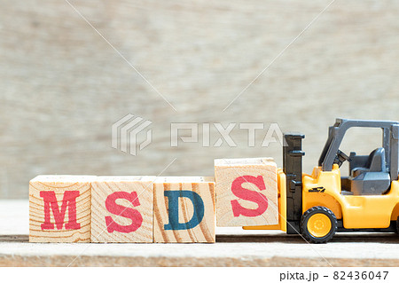 Toy forklift hold letter block S to complete word MSDS (Abbreviation of material safety data sheet) on wood background 82436047