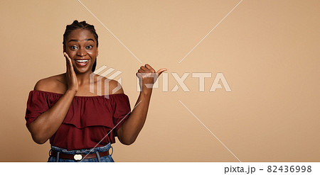 Surprised african american millennial woman pointing at copy space 82436998