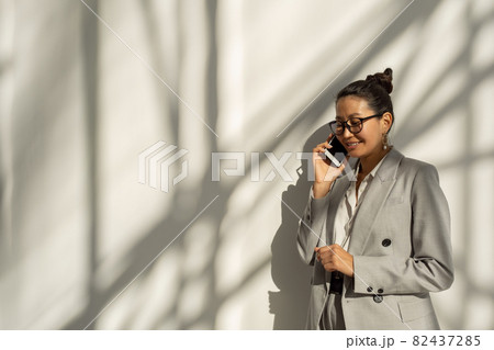 Happy young Asian businesswoman speaking on mobile phone Happy young Asian businesswoman speaking on mobile phone 82437285