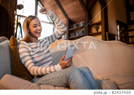 Excited woman using phone shaking clenched fist Excited woman using phone shaking clenched fist 82437430