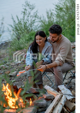 Happy young couple spending time by campfire 82437484