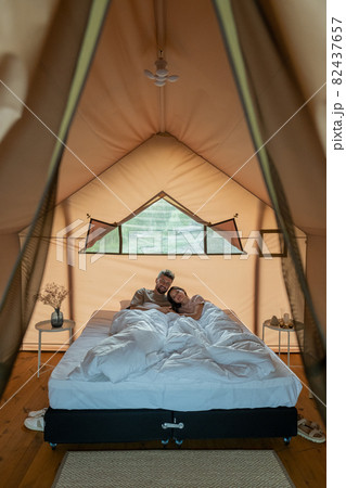 Young amorous couple resting in bed under white blanket Young amorous couple resting in bed under white blanket 82437657