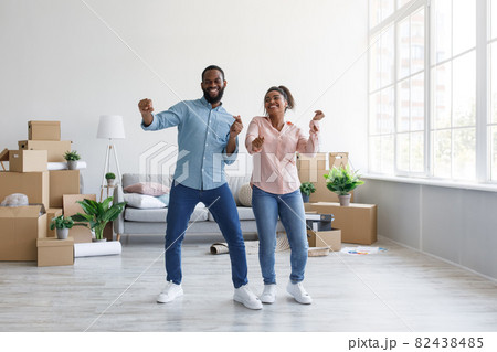 Satisfied young afro american couple dancing in flat with cardboard boxes in home interior, free space 82438485