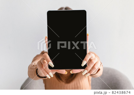 Millennial woman showing digital tablet with blank screen on white studio background, mockup for website or app Millennial woman showing digital tablet with blank screen on white studio background, mockup for website or app 82438674