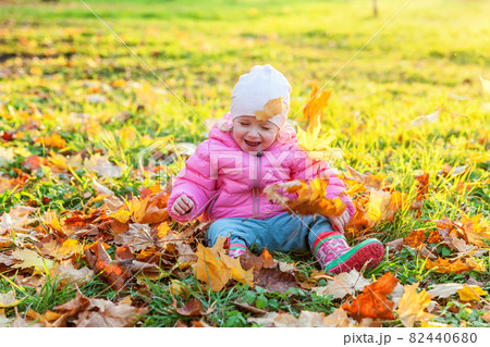 Happy young girl playing under falling yellow leaves in beautiful autumn park on nature walks outdoors. Little child throws up autumn orange maple leaves. Hello autumn concept. Happy young girl playing under falling yellow leaves in beautiful autumn park on nature walks outdoors. Little child throws up autumn orange maple leaves. Hello autumn concept. 82440680
