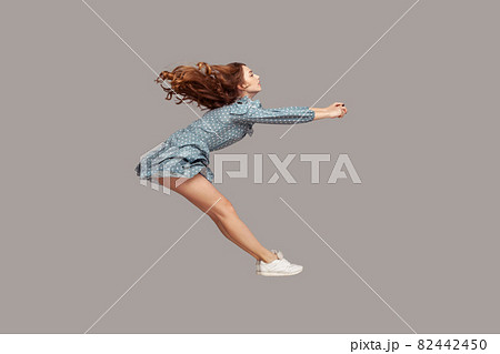 Side view girl rushing at full speed accelerate, steering driving fast and levitating in air. Model flying rapidly 82442450