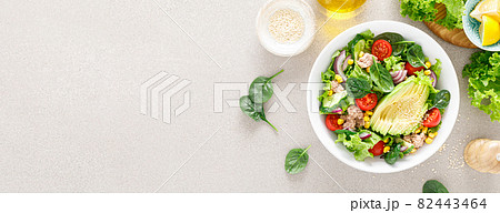 Avocado and tuna fresh vegetable salad with tomato, cucumber corn, onion, lettuce and spinach. Healthy and detox food concept. Ketogenic diet. Buddha bowl dish on light background, top view. Banner. Avocado and tuna fresh vegetable salad with tomato, cucumber corn, onion, lettuce and spinach. Healthy and detox food concept. Ketogenic diet. Buddha bowl dish on light background, top view. Banner. 82443464