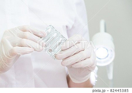 Doctor wearing medical gloves holding a pack of rectal or vaginal suppositories 82445385