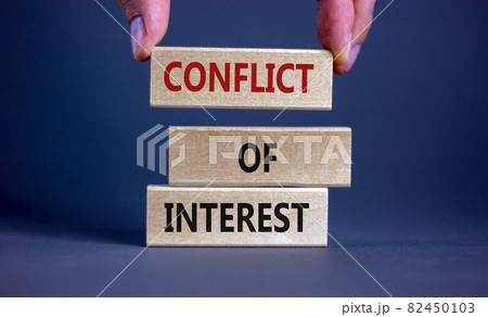 Conflict of interest symbol. Businessman hand. Wooden blocks with words 'conflict of interest'. Beautiful grey background. Copy space. Business and conflict of interest concept. 82450103