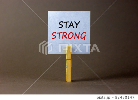 Stay strong symbol. Wooden clothespin with white sheet of paper. Words 'stay strong'. Beautiful grey background. Motivational, business and stay strong concept. Copy space. Stay strong symbol. Wooden clothespin with white sheet of paper. Words 'stay strong'. Beautiful grey background. Motivational, business and stay strong concept. Copy space. 82450147
