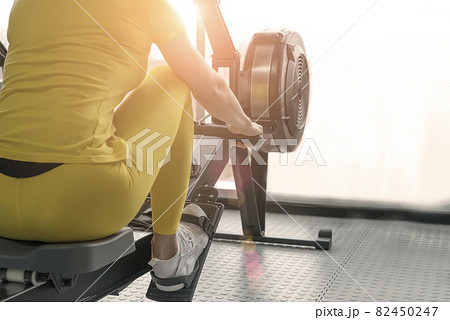Back view of woman uses a rowing machine 82450247