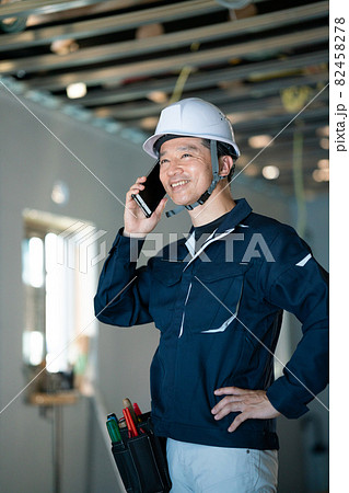 建築現場でスマホで話をする職人 82458278