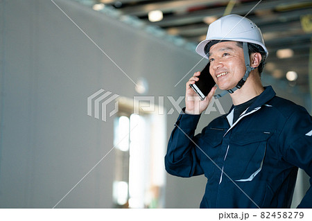 建築現場でスマホで話をする職人 82458279
