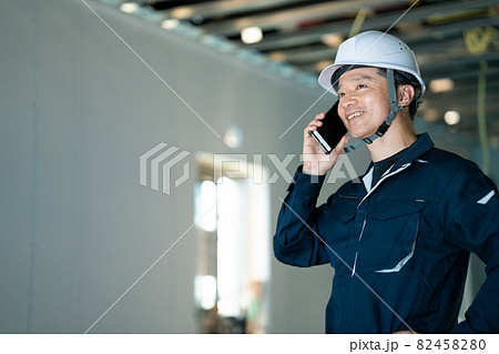 建築現場でスマホで話をする職人 82458280