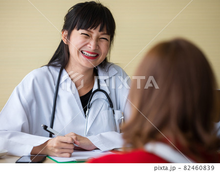 Asian doctor toothy smile to patient after explaining illness was positive. She likes representative pharmaceutical. Her happy face and advisor good for health care business. 82460839