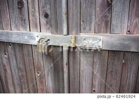 古い木製の扉の閂に付けられた錠前 82461924