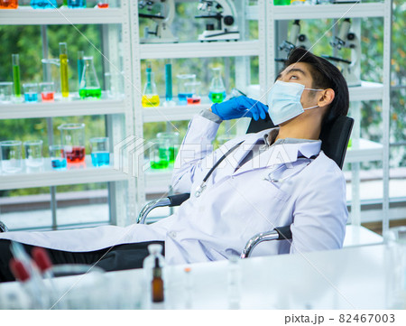 Doctor wearing protective mask feels tired during working for giving coronavirus vaccine to people, lay down and sleep on chair with exhausted gesture. Medical team hard work in outbreak concept 82467003