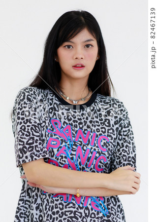 Portrait of an Asian woman with long black hair Wears a black and white striped T-shirt. Standing with arms folded and smiling looking at a camera confidently shoot with white background in a studio 82467139