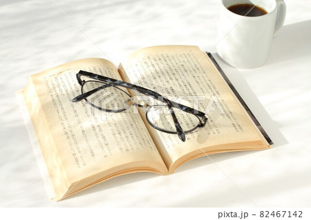 陽射しの中の本と眼鏡とコーヒー 82467142