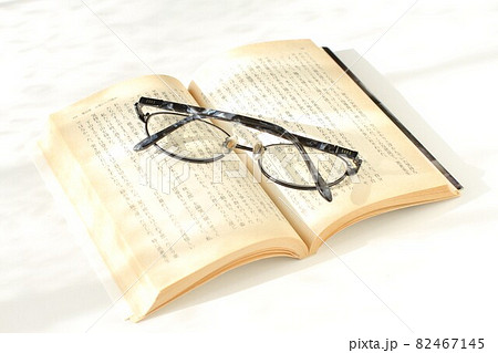 陽射しの中の本とメガネ、白バック 82467145