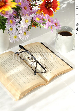 窓辺の本とコーヒー、花瓶の花 82467147