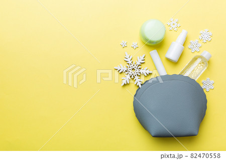 Christmas flat lay with makeup cosmetic products in cosmetic bag on colored background. Top view New year Beauty concept 82470558
