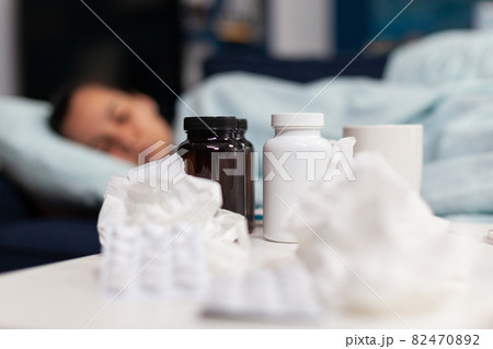 Close up of bottles and pills for sick woman with virus Close up of bottles and pills for sick woman with virus 82470892