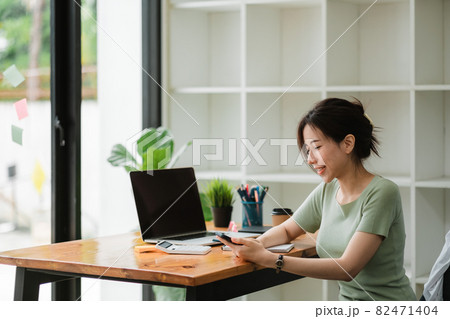 Happy asian woman using mobile phone at modern office 82471404