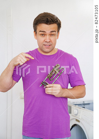 repairman of washing machine holds old tubular electric heater repairman of washing machine holds old tubular electric heater 82473105