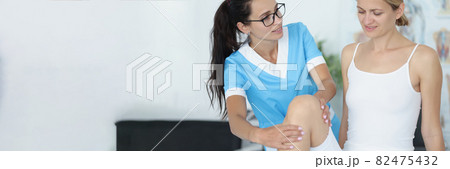 Female doctor conducts a physical examination of knee joint of patient 82475432