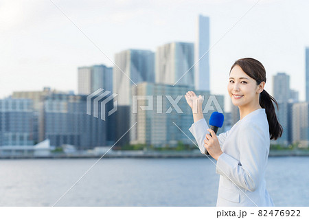 都市の前に立つ女性アナウンサー 82476922