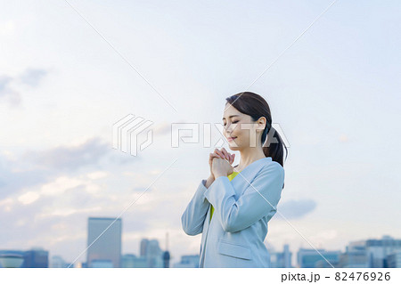 都市の前で祈る女性 82476926