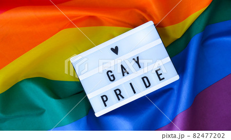 Rainbow flag with lightbox and text GAY PRIDE. Rainbow lgbtq flag made from silk material. Symbol of LGBTQ pride month. Equal rights. Peace and freedom 82477202