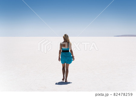 blonde woman dressed in blue walking on a salt lake 82478259