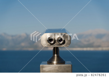 coin operated binoculars in front of mountains and sea 82478261