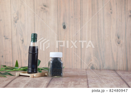 Black Cumin in a container with oil in a jar on table. Black Cumin in a container with oil in a jar on table. 82480947