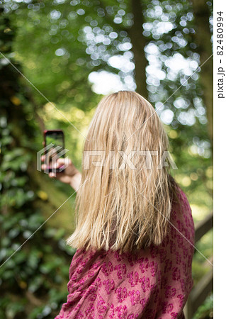 Woman taking pictures with smartphone in the forest 82480994