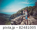 A young girl holds a smartphone to take pictures of a beautiful mountain landscape 82481005