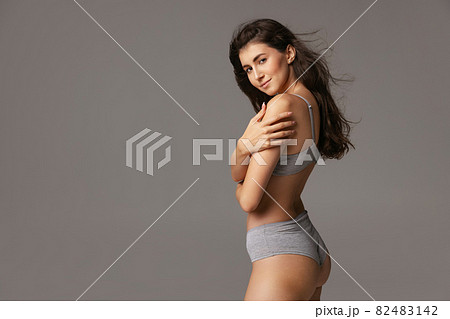 Half-length portrait of young beautiful slim woman in lingerie isolated over gray studio background. Natural beauty concept. Half-length portrait of young beautiful slim woman in lingerie isolated over gray studio background. Natural beauty concept. 82483142