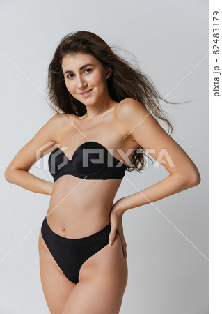Portrait of young beautiful slim woman in lingerie posing isolated over gray studio background. Natural beauty concept. 82483179