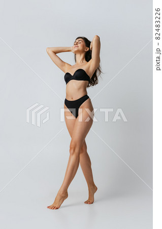 Portrait of young beautiful slim woman in lingerie posing isolated over gray studio background. Natural beauty concept. 82483226